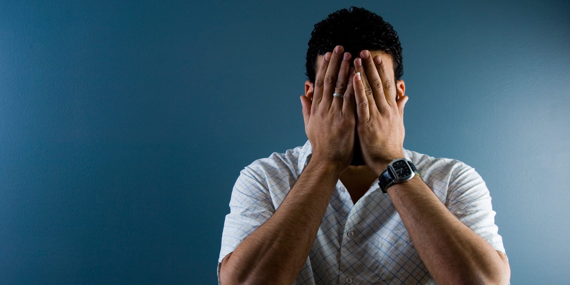 A3DATJ Contemporary image of a man hiding his face indoors